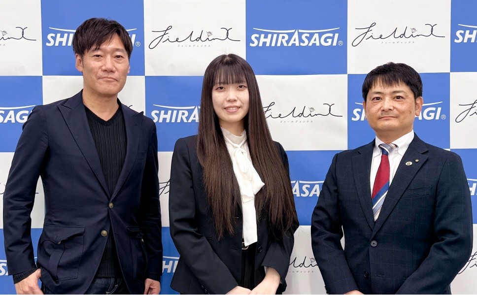 記念写真。フォーマルな姿の男性と株式会社FieldinX代表取締役と白鷺ホールディングス株式会社代表取締役社長が並んでいる。