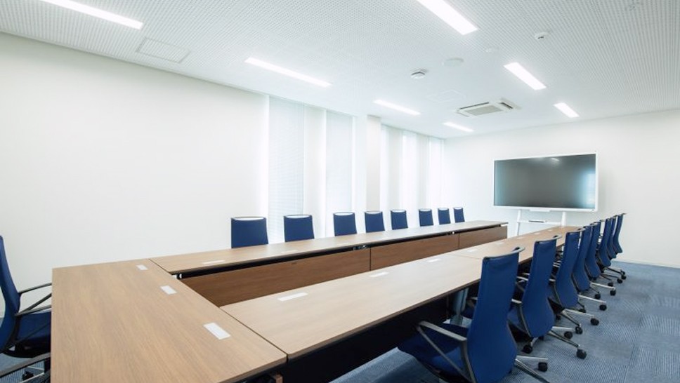中会議室の写真。長テーブルと椅子がコの字に並んでいて、大きなディスプレイが設置されている。